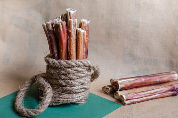 A group of several dried bully sticks on a textured light brown background